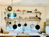 A kitchen scene with the BOLA recycled-glass pendant to the left, shining bright and radiating with blue light.
