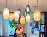 Julie Conway standing in a modern interior setting with hanging pendant lights.