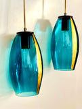 Two blue pendant lights with gold-leaf strip upgrades hanging against a white wall.