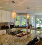 Modern kitchen with granite countertops, gas stove, and silver-leaf illuminating pendant lights.