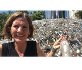 Julie Conway, the creator of LUMI collection, in front of a pile of bottles and other plastic and glass containers to showcase her process of recycling in the making of BOLA recycled glass pendants.