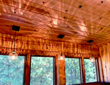 Three ACQUA clear glass pendant lights in a wood cabin with large windows and speckles of light radiating the cabin