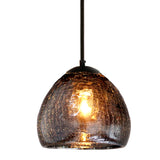 A smokey colored recycled glass pendant with a radiating warm light on a white background