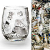 A glass featuring silver leaf detailing with on a white background next to a pile of used glass, showing the glass to be made out of recycled glass.