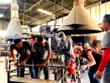 Julie Conway, the owner of Lumi Collection, in a glass blowing shop, making a BOLA recycled-glass pendant.