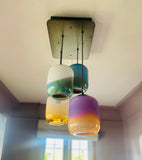 Modern chandelier with colorful glass pendants in a room setting.