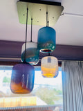 Three colorful glass pendant lights hanging from a ceiling with beautiful gradients.