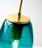 A teal and gold metal ELETTRA glass oval pendant light close-up on a white background