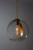 A sphere glass pendant light with a gold leaf detailing, hanging from a metal chain in low lighting with a dark grey background