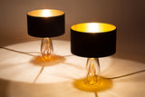 Two SERAFINA glass lamps with black tops, casting warm spotlights upon a light tan background