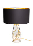 A classy glass lamp with a black top and gold colored cording on a white background