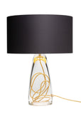 A chic black top, clear glass base, and gold cording SERAFINA lamp from Julie Conway's LUMI collection on a white background