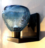A wall-mounted sconce with a peacock blue crackle glass globe on a bent metal bracket.