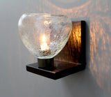 A wall-mounted sconce with a clear crackle glass globe on a bent metal bracket.