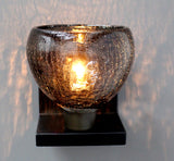 A small, cracked-glass-pattern grey sconce from the Lumi ACQUA collection, creating an amazing warm light effect on a white wall