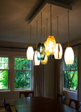 Dinning room setting with 9 pendants celadon, gold-leaf, and blue installed, all of which turned on to create a strong yet calming glow.