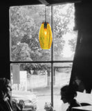 Yellow topaz glass pendant in a black and white cafe scene infront of a window.