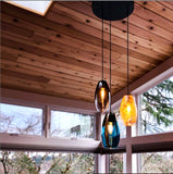 A cabin scene with three uniquely colored hand-blown glass pendants.