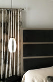 An opaline ELETTRA glass pendant with a luxury silver contour stripe upgrade in a bedroom scene.