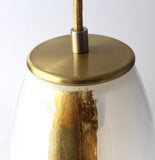 A close-up of the brass metal finish of an opaline ELETTRA pendant light.